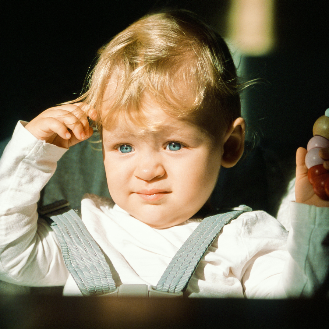 Baby in de zon blond haar blauwe ogen